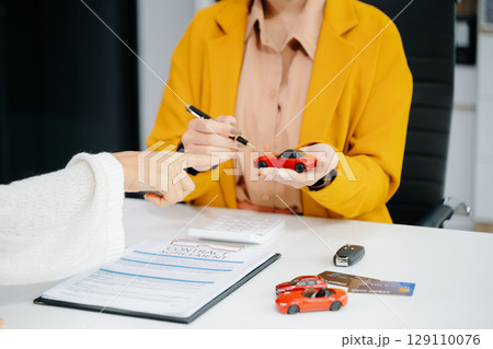 Asian people car salesman or sales manager offers to sell a car and explains of signing a car contract and signing car insurance Asian people car salesman or sales manager offers to sell a car and explains of signing a car contract and signing car insurance 129110076