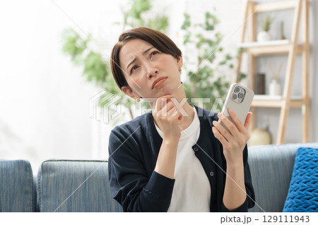 スマホを持って悩む女性 スマホを持って悩む女性 129111943
