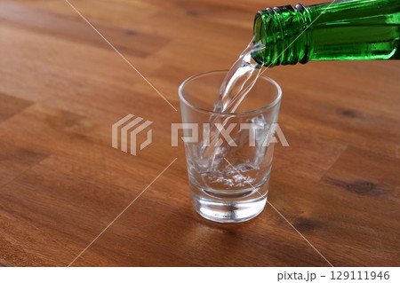 韓国焼酎（ソジュ） - 韓国の伝統的な蒸留酒、よく冷えた韓国焼酎（ソジュ）をグラスに注ぐ 129111946