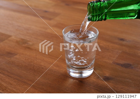 韓国焼酎(ソジュ) - 韓国の伝統的な蒸留酒、よく冷えた韓国焼酎(ソジュ)をグラスに注ぐ 韓国焼酎(ソジュ) - 韓国の伝統的な蒸留酒、よく冷えた韓国焼酎(ソジュ)をグラスに注ぐ 129111947