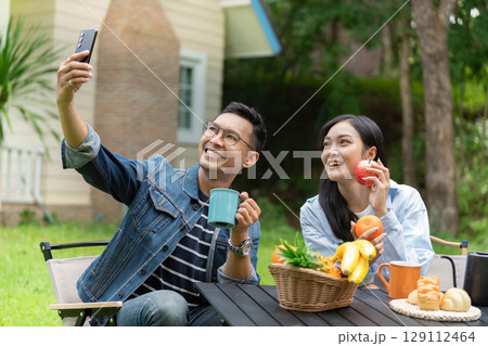 Joyful couple enjoying outdoor moments with fruits and drinks 129112464