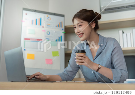 Remote Work. Smiling woman using laptop for business tasks. 129112499