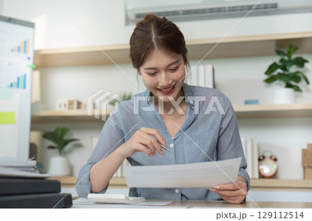 Businesswoman reviewing financial documents with a smile Businesswoman reviewing financial documents with a smile 129112514