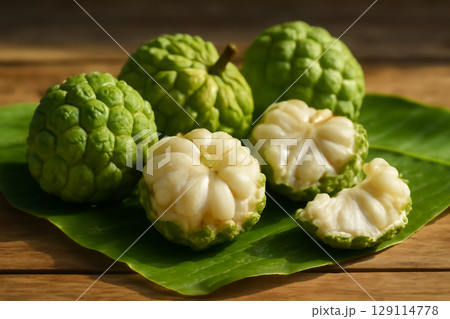AI generated close-up of fresh sugar apple fruits on banana leaves, with peeled fruit revealing juicy flesh. Vibrant sunlight and water droplets on the fruits create a natural tropical atmosphere 129114778