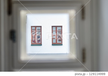 Windows of a cozy building framed by a wooden window in a serene urban setting 129114999