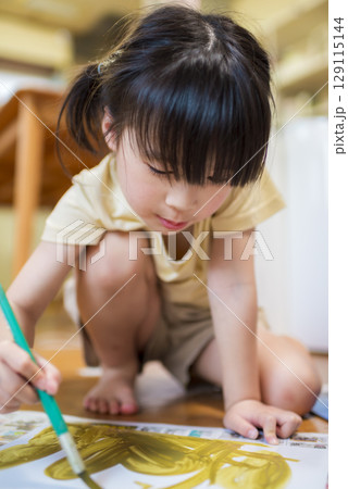 室内で絵の具を使ってお絵描きを楽しむ元気な女の子 129115144