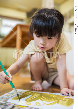 室内で絵の具を使ってお絵描きを楽しむ元気な女の子 129115145