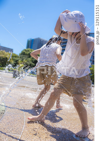 夏の日差しの中で噴水で水遊びを楽しむ子ども 129115151