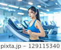ジムのランニングマシンで走る若い女性 129115340