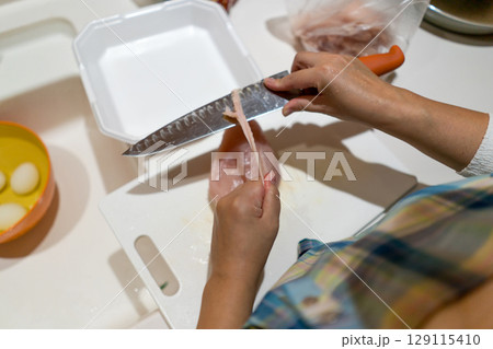 鶏むね肉を切る主婦 129115410