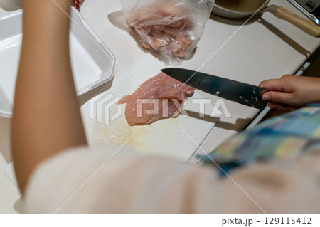 鶏むね肉を切る主婦 129115412