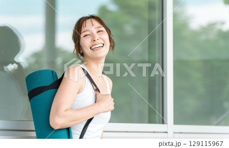 ヨガマットを持ったヨガ講師の女性・ヨガ・ピラティスをする女性 ヨガマットを持ったヨガ講師の女性・ヨガ・ピラティスをする女性 129115967