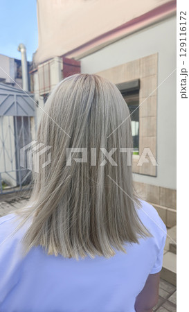 Woman with long light dyed hair standing in beauty salon with back. Ash shade. 129116172