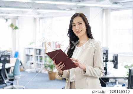 オフィスで仕事をする若いビジネスウーマン オフィスで仕事をする若いビジネスウーマン 129116530