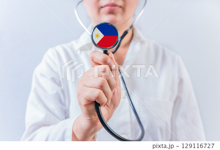 Female doctor holding stethoscope with Philippines flag. National health system of Philippines Female doctor holding stethoscope with Philippines flag. National health system of Philippines 129116727