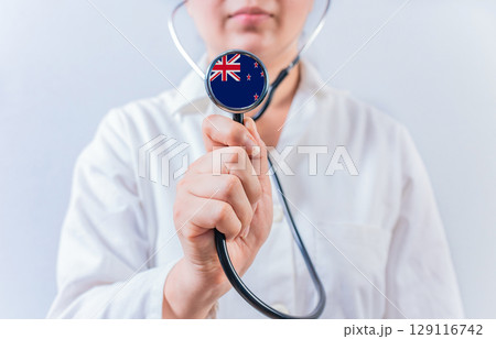 Female doctor holding stethoscope with New Zealand flag. National health system of New Zealand Female doctor holding stethoscope with New Zealand flag. National health system of New Zealand 129116742