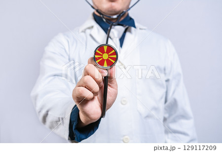 Doctor hands holding stethoscope with North Macedonia flag. North Macedonia health and care concept Doctor hands holding stethoscope with North Macedonia flag. North Macedonia health and care concept 129117209
