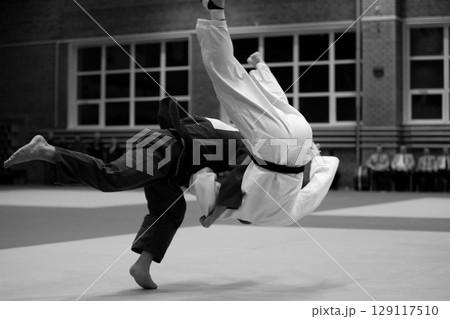 judoka in dark gi is executing high-impact throw on his opponent in white gi judoka in dark gi is executing high-impact throw on his opponent in white gi 129117510