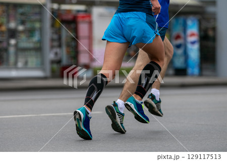 two male athletes runnnig marathon side by side in streets city 129117513