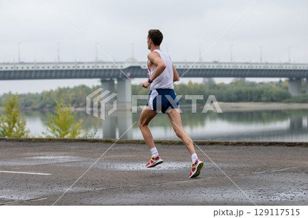 runner wearing sleeveless shirt and shorts, captured on cloudy day with large bridge and river runner wearing sleeveless shirt and shorts, captured on cloudy day with large bridge and river 129117515