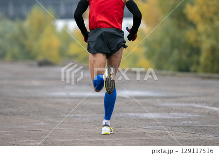 back view man running marathon in long sleeve and compression socks 129117516