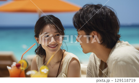 夏のビーチリゾート　パラソルの下で楽しんでいる男女 129118719