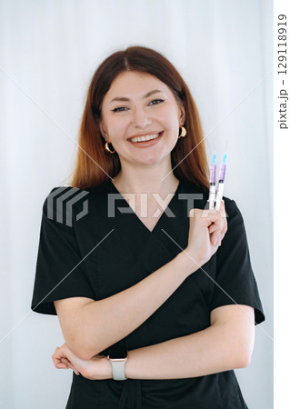 skilled aesthetician woman professional wearing black medical suit holding syringes 129118919