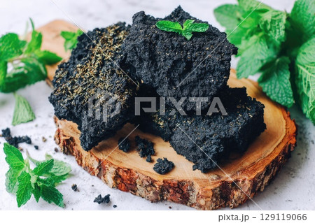 shilajit rock placed on a rough-cut wooden board with visible grain. 129119066