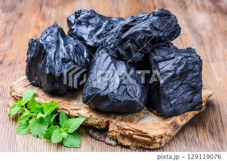shilajit resin placed on a rough-cut wooden board with visible grain. 129119076