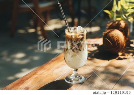 Vietnamese coconut coffee in a tall glass on wooden table, coconuts next to glass Vietnamese coconut coffee in a tall glass on wooden table, coconuts next to glass 129119199
