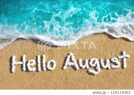 turquoise sea water on sand beach with text made with white pebbles 'Hello August' 129119362
