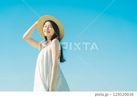 青空背景の夏服の女性 129120016