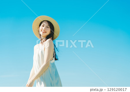 青空背景の夏服の女性 129120017