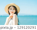 海と青空バックの麦わら帽子を被った女性 129120291