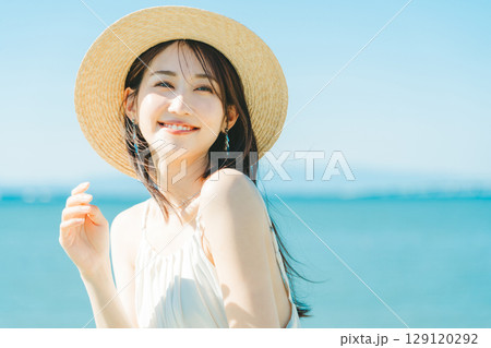 海と青空バックの麦わら帽子を被った女性 129120292