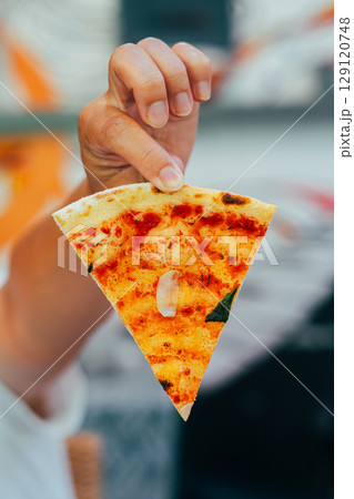 Hand Holding Slice of Hot Ham and Cheese Pizza 129120748