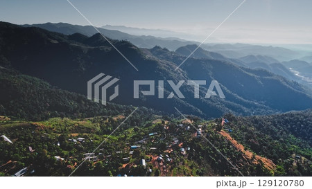 Lush green forested mountains surrounding a small village in rural Chiang Mai Province, Thailand, showcasing the natural beauty and remote settlements of Southeast Asia Lush green forested mountains surrounding a small village in rural Chiang Mai Province, Thailand, showcasing the natural beauty and remote settlements of Southeast Asia 129120780