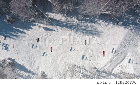 Aerial drone of ski lift, snowy mountain slope, surrounded by snow covered trees, on a sunny winter day, tranquil and picturesque view. Bukovel ski resort. Winter wild nature travel background 129120836