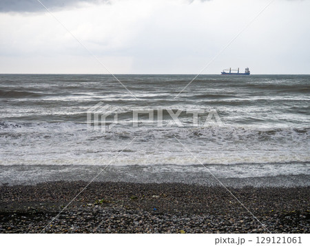 lonely ship in the middle of a rough sea. Barge in the distance. Big waves on the sea. After the storm. Bad weather.  Ship on the horizon 129121061