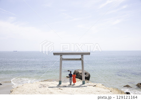 海岸沿いの鳥居の前に立つふたり 海岸沿いの鳥居の前に立つふたり 129121164