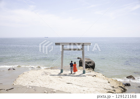 海岸沿いの鳥居の前に立つふたり 海岸沿いの鳥居の前に立つふたり 129121168