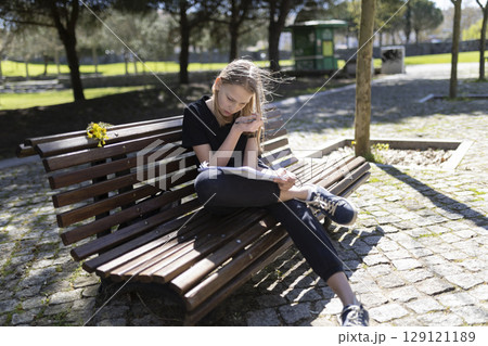 Young student girl studying outdoors on park bench Young student girl studying outdoors on park bench 129121189