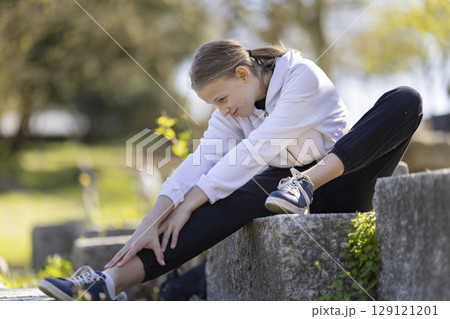Young girl stretching legs outdoors in a park 129121201