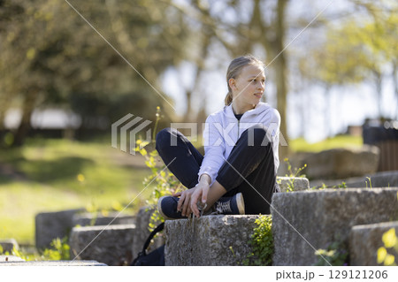 Girl sitting in a park enjoying the sunny day 129121206
