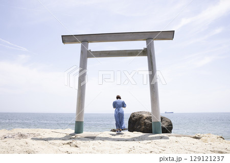 海岸沿いの鳥居の前に立つ女性 129121237