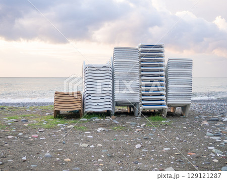 Folded sun loungers. End of season  at the resort concept . The rest is over. Sunbeds stacked on top of each other. Business on the seashore. Services for a comfortable holiday on the beach. 129121287