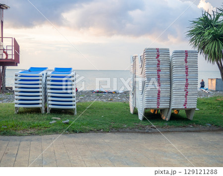 Folded sun loungers. End of season  at the resort concept . The rest is over. Sunbeds stacked on top of each other. Business on the seashore. Services for a comfortable holiday on the beach. 129121288
