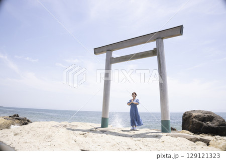 海岸沿いの鳥居の前に立つ女性 129121323