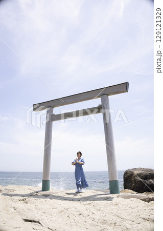 海岸沿いの鳥居の前に立つ女性 129121329