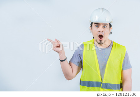 Surprised engineer constructor pointing side advertising space isolated. Amazed engineer pointing to the side an advertising space Surprised engineer constructor pointing side advertising space isolated. Amazed engineer pointing to the side an advertising space 129121330
